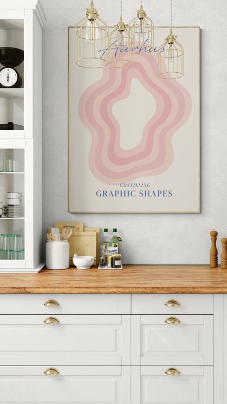 Plakat z napisem "Aarhus" i różowym graficznym wzorem zawieszony nad drewnianym blatem w klasycznej białej kuchni z witrynką i złotymi dodatkami