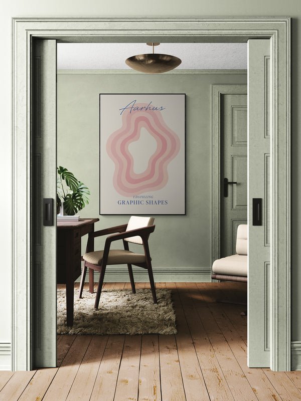 Plakat z napisem "Aarhus" i graficznym wzorem w odcieniach różu zawieszony na ścianie eleganckiego gabinetu z biurkiem, krzesłem i dywanem