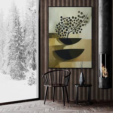 Abstrakcyjna grafika ścienna z czarnymi misami i gałązką na beżowym tle, zawieszona w przytulnym salonie z drewnianą ścianą, kominkiem i widokiem na ośnieżony las.