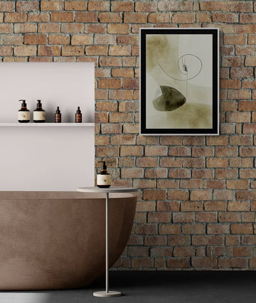 Abstrakcyjny plakat w czarnej ramie na ceglanej ścianie w nowoczesnej łazience z brązową wanną i minimalistycznym stolikiem