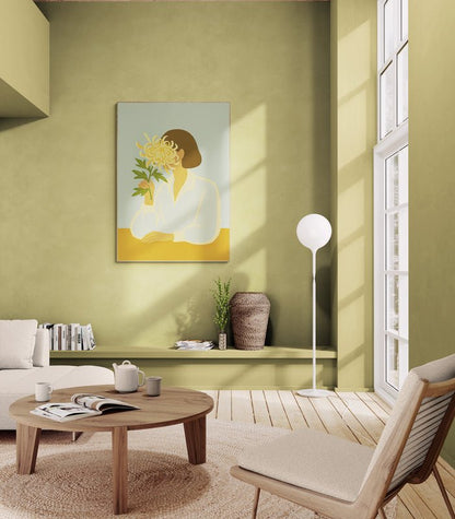 Plakat z ilustracją kobiety trzymającej chryzantemę, zawieszony na zielonej ścianie w przytulnym salonie z jasnymi meblami i okrągłym stolikiem