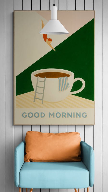 Plakat z napisem "Good Morning" i filiżanką kawy zawieszony na ścianie z białymi panelami nad niebieskim fotelikiem z brązową poduszką