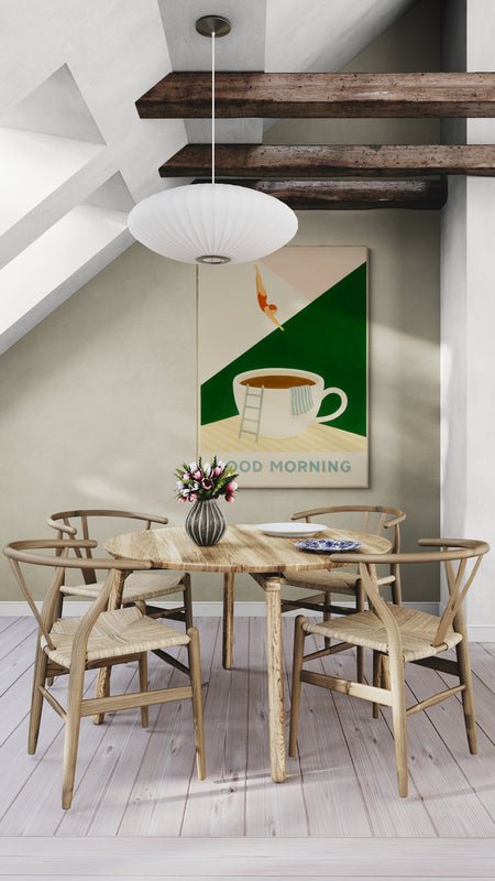 Plakat z napisem "Good Morning" i ilustracją filiżanki kawy, zawieszony na ścianie w jadalni na poddaszu z drewnianym stołem i belkami sufitowymi