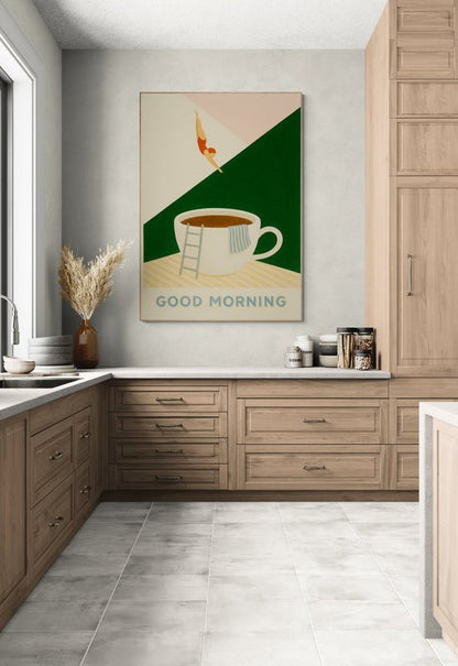 Plakat z napisem "Good Morning" i ilustracją filiżanki kawy, do której skacze postać, zawieszony na ścianie w nowoczesnej kuchni z drewnianymi szafkami