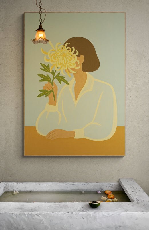 Plakat z ilustracją kobiety trzymającej dużą chryzantemę, zawieszony na ścianie nad kamienną wanną z wodą i pływającymi kwiatami